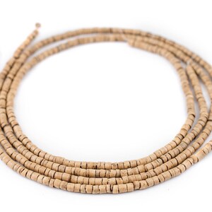 Puede incluir: Una hebra de cuentas de madera natural de color marr&oacute;n claro. Las cuentas son peque&ntilde;as y redondas, y est&aacute;n enhebradas en un cord&oacute;n fino. La hebra est&aacute; enrollada en un c&iacute;rculo.