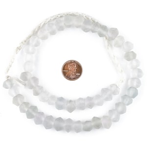 May include: A strand of opaque white glass beads with a faceted, hexagonal shape. The beads are strung on a white cord and are approximately the size of a US penny.
