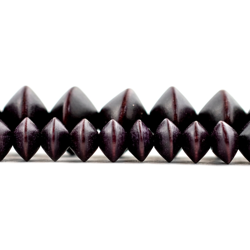 Puede incluir: Primer plano de una fila de cuentas de madera marr&oacute;n oscuro con punta. Las cuentas est&aacute;n dispuestas en un patr&oacute;n escalonado.