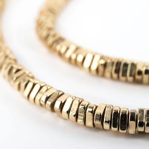 Puede incluir: Un collar de oro hecho de pequeñas cuentas hexagonales.