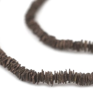 Peut inclure: Un collier en bois brun composé de perles plates et rectangulaires.
