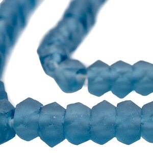 May include: A strand of blue glass beads with a faceted, irregular shape. The beads are strung on a clear thread.