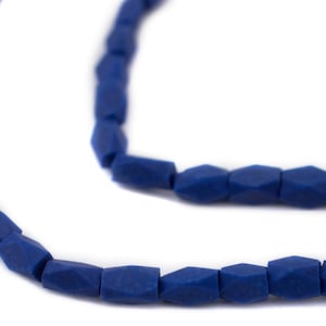 May include: Close-up of a necklace with dark blue, faceted beads. The beads are strung together, creating a curved line against a white background. The necklace is a jewelry item.