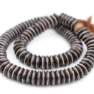 May include: A brown and white beaded necklace with a brown tassel. The beads are round and have a striped pattern.