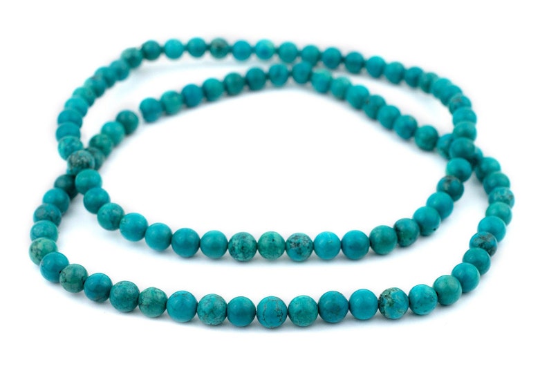 May include: A strand of turquoise beads, a popular choice for jewelry making. The beads are a vibrant blue-green color and have a smooth, polished finish.