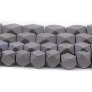 Puede incluir: Una hebra de cuentas de piedra preciosa facetadas grises. Las cuentas tienen forma de cubo con un corte de diamante en cada lado.