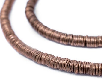 Puede incluir: Primer plano de un collar de color cobre hecho de pequeñas cuentas redondas y planas. Las cuentas están apiladas una encima de la otra para crear una hebra larga y continua.