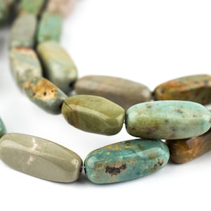 May include: Close-up of a necklace featuring oblong beads in shades of green, turquoise, and brown. The beads have a polished, natural stone appearance, strung together to form a necklace.