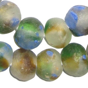 May include: Close-up of a strand of colorful, irregular glass beads. The beads are a mix of translucent colors, including blue, green, yellow, and brown, with small blue spots. The beads are strung together, creating a textured and organic look.