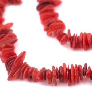 May include: A strand of red coral beads, each bead is a flat, irregular shape.