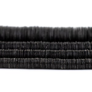 Könnte beinhalten: Eine Schnur schwarzer runder Perlen aus natürlichen Materialien mit rauer Textur. Die Perlen sind in Reihen gestapelt und erzeugen einen geschichteten Effekt.