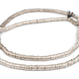 Pu&ograve; includere: Una collana d'argento fatta di piccole perline rotonde e piatte. Le perline sono collegate tra loro per formare una lunga catena continua.