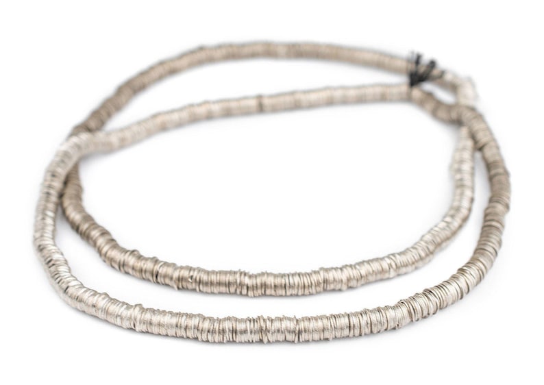Pu&ograve; includere: Una collana d'argento fatta di piccole perline rotonde e piatte. Le perline sono collegate tra loro per formare una lunga catena continua.