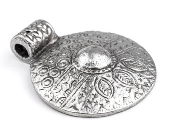 May include: A silver pendant with an intricate design featuring a central circle surrounded by smaller circles and geometric patterns.