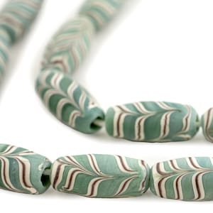 May include: Close-up of a strand of antique glass beads. The beads are a pale teal colour with white and brown striped patterns. The beads are oval-shaped and have a hole running through the centre for stringing.
