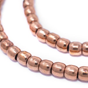 May include: A close-up of a strand of copper beads. The beads are round and have a shiny, metallic finish.