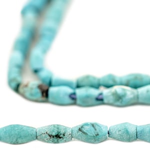 Puede incluir: Primer plano de un collar de cuentas turquesas. Las cuentas son de color azul verdoso claro con variaciones naturales en la piedra. Las cuentas están ensartadas, creando un collar o una pulsera.