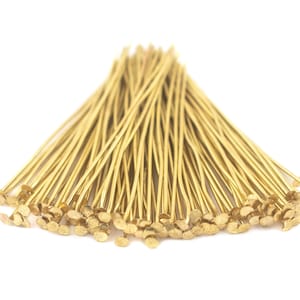 May include: A bunch of gold-coloured head pins with flat heads. The pins are arranged in a fan shape.