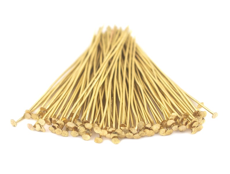 May include: A bunch of gold-coloured head pins with flat heads. The pins are arranged in a fan shape.