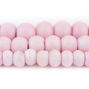 May include: A strand of pink glass beads. The beads are round and have a slightly irregular shape. They are strung together on a clear thread.