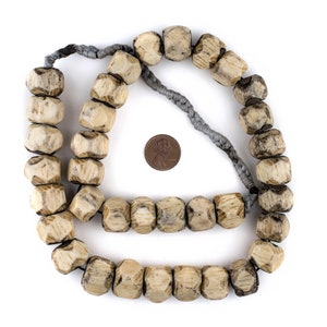 May include: A string of light brown wooden beads with a grey cord. The beads are faceted and have a worn, rustic look. The string of beads is about 50 cm long.