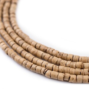 Puede incluir: Primer plano de una hebra de cuentas de madera de color marr&oacute;n claro. Las cuentas son redondas y tienen un aspecto natural y r&uacute;stico.