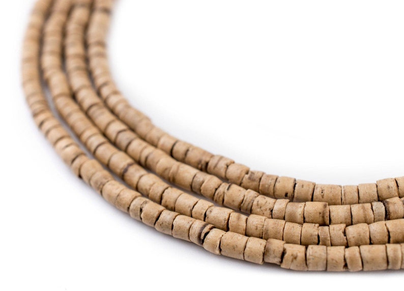 Puede incluir: Primer plano de una hebra de cuentas de madera de color marr&oacute;n claro. Las cuentas son redondas y tienen un aspecto natural y r&uacute;stico.