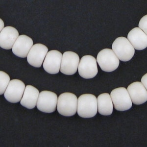 May include: Close-up of two strands of off-white, rounded beads against a dark background. The beads are evenly spaced and have a smooth, matte finish. The beads appear to be strung together, creating a necklace or bracelet.