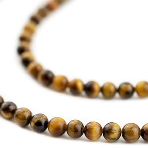 Peut inclure: Un collier de perles en pierre d'œil de tigre. Les perles sont rondes, avec un mélange de couleurs brun doré et brun foncé. Les perles sont enfilées ensemble, créant un collier ou un bracelet.