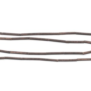 Pu&ograve; includere: Una collana di perline di legno marroni, ogni perlina ha una forma cilindrica.