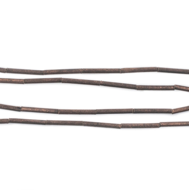 Pu&ograve; includere: Una collana di perline di legno marroni, ogni perlina ha una forma cilindrica.