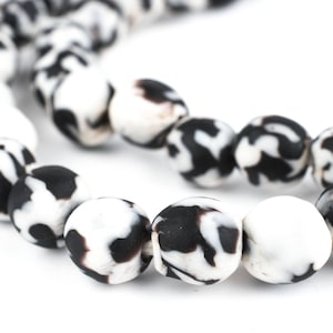 May include: A strand of black and white patterned beads. The beads are round and have a mottled appearance.