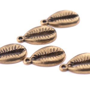 May include: Five gold-colored metal cowrie shell charms with a hole at the top for attaching to jewelry or other crafts.
