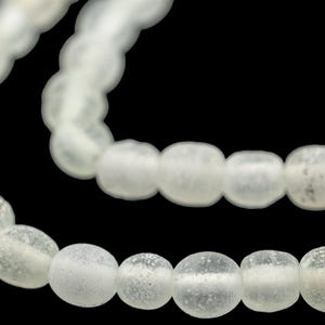 May include: A strand of white glass beads with a frosted finish. The beads are round and have a slightly irregular shape.