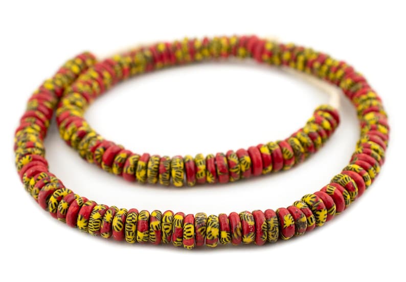 May include: A strand of red and yellow beads with a black geometric pattern. The beads are round and have a slightly flattened shape.