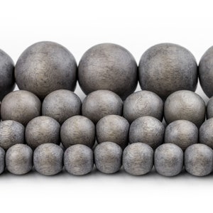 May include: A collection of gray wooden beads of various sizes, arranged in a staggered pattern. The beads are smooth and have a matte finish.