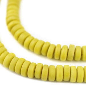 May include: A strand of yellow wooden beads, each bead is round and slightly flattened, creating a cylindrical shape.