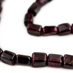 May include: A strand of dark purple gemstone beads, each bead is faceted and has a rectangular shape.