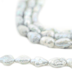 May include: A strand of white baroque pearls, with an irregular shape and a slightly iridescent sheen.