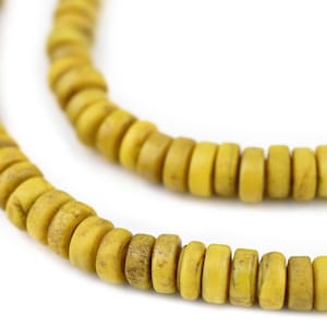 Może przedstawiać: Szereg żółtych koralików wykonanych z naturalnych materiałów. Koraliki są okrągłe i mają lekko szorstką fakturę.