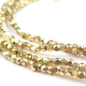 May include: A strand of gold-colored metal beads. The beads are faceted and have a slightly irregular shape.