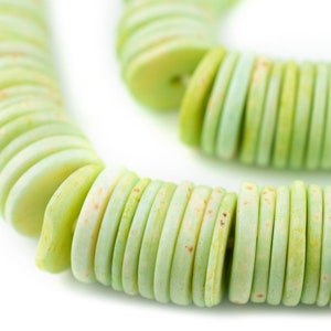 May include: A strand of light green and white round beads, stacked and arranged in a circular pattern.