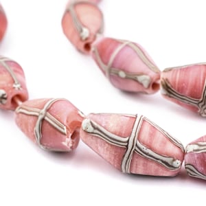 以下が含まれることがあります： 銀色の格子模様が施されたピンク色のビーズの連のクローズアップ。ビーズは楕円形で、わずかに半透明に見えます。背景は白です。