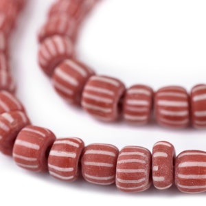 May include: A strand of red and white striped glass beads. The beads are cylindrical and have a matte finish.