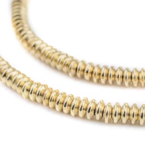 Puede incluir: Un collar de cadena de oro hecho de pequeñas cuentas redondas. Las cuentas están dispuestas en espiral.