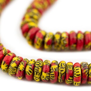 May include: A strand of red and yellow glass beads with a black geometric pattern. The beads are round and have a slightly flattened shape.