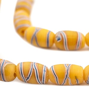 Könnte beinhalten: Eine Kette aus gelben, blauen und weißen, gestreiften Glasperlen. Die Perlen sind oval geformt und haben eine glänzende Oberfläche.