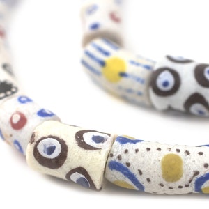 May include: A string of white, cylindrical beads with colourful, hand-painted designs. The beads feature blue, red, yellow, and black patterns, including dots, stripes, and abstract shapes. The beads are strung together, creating a unique accessory.