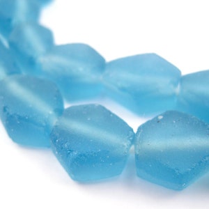 May include: A strand of light blue glass beads with a faceted, irregular shape. The beads are translucent and have a frosted finish.