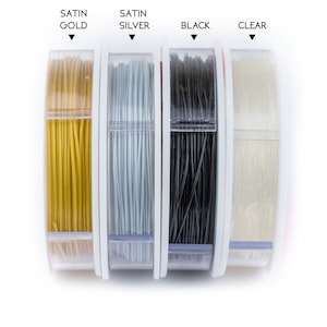 Puede incluir: Cuatro carretes de hilo en diferentes colores: oro satinado, plata satinada, negro y transparente. Los carretes est&aacute;n etiquetados con sus colores respectivos.